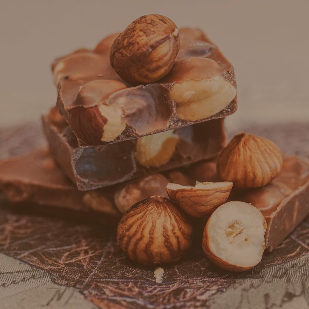Ganze Haselnüsse und Mandeln, kunstvoll arrangiert auf groben Schokoladenstücken
