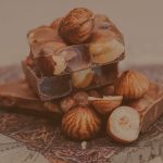 Ganze Haselnüsse und Mandeln, kunstvoll arrangiert auf groben Schokoladenstücken