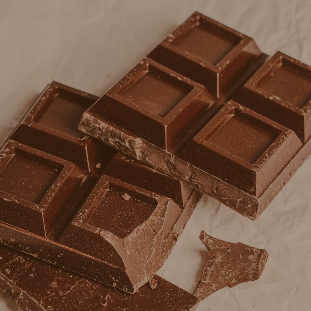 Zerbrochene Stücke einer dunklen Schokoladentafel in rustikaler Anordnung